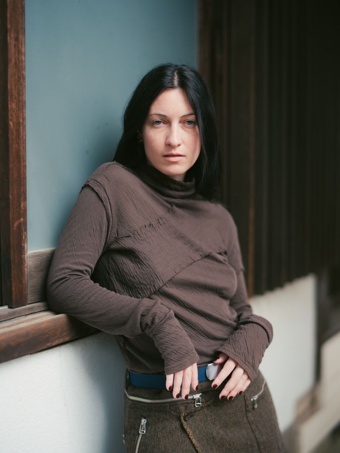 Leaning at a window in brown knit