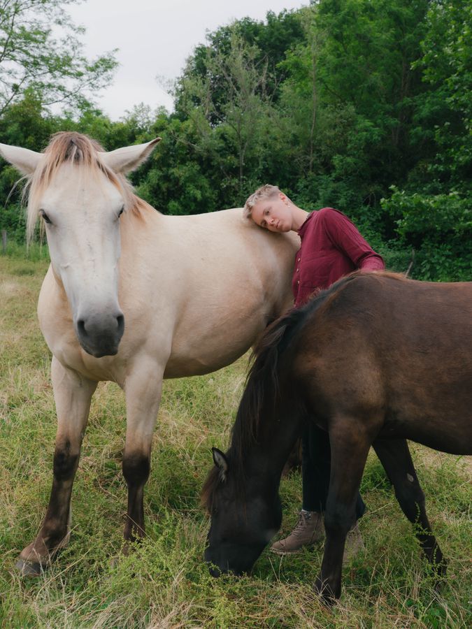 Resting against a horse in a field