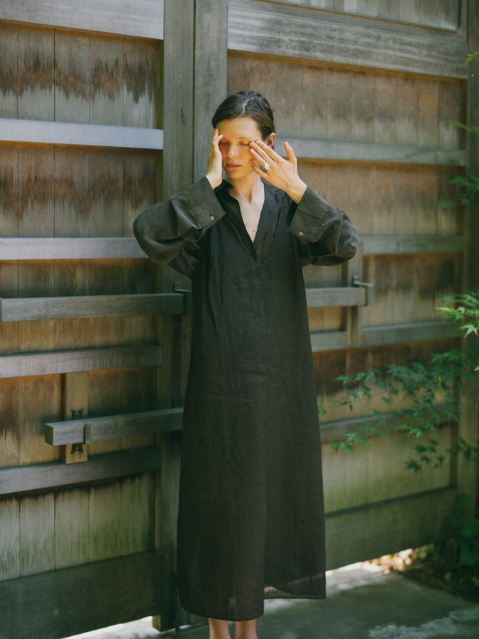 Dark coat with a hand raised to the face