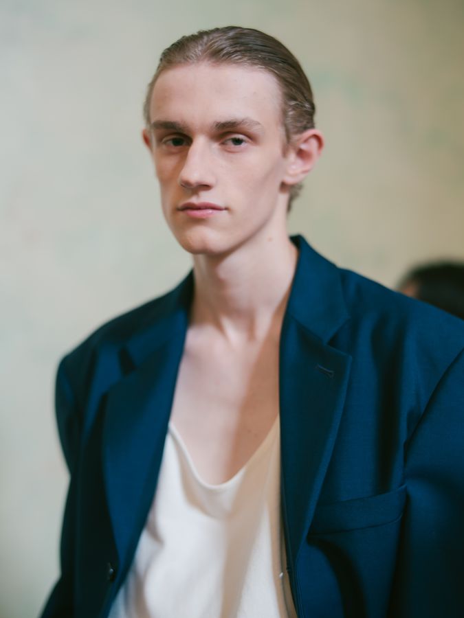 Model in a navy jacket and white vest, backstage