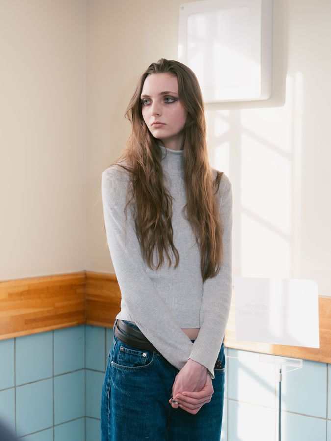 By the window in a pale turtleneck