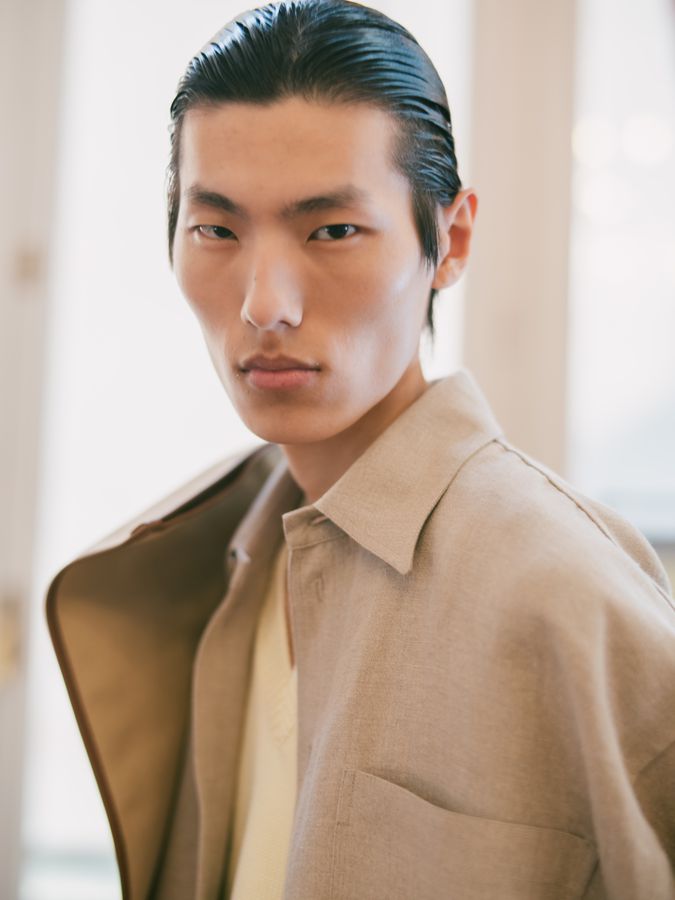 Model in a beige shirt and coat, backstage